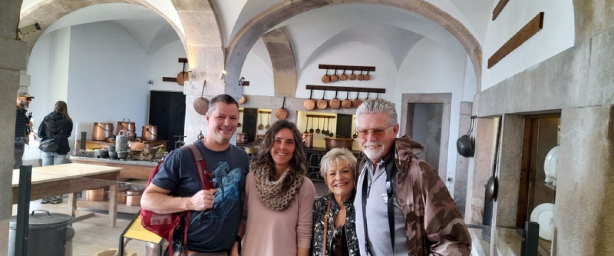 A cheerful group of people smiles for a photo in the historic kitchen of Pena Palace.