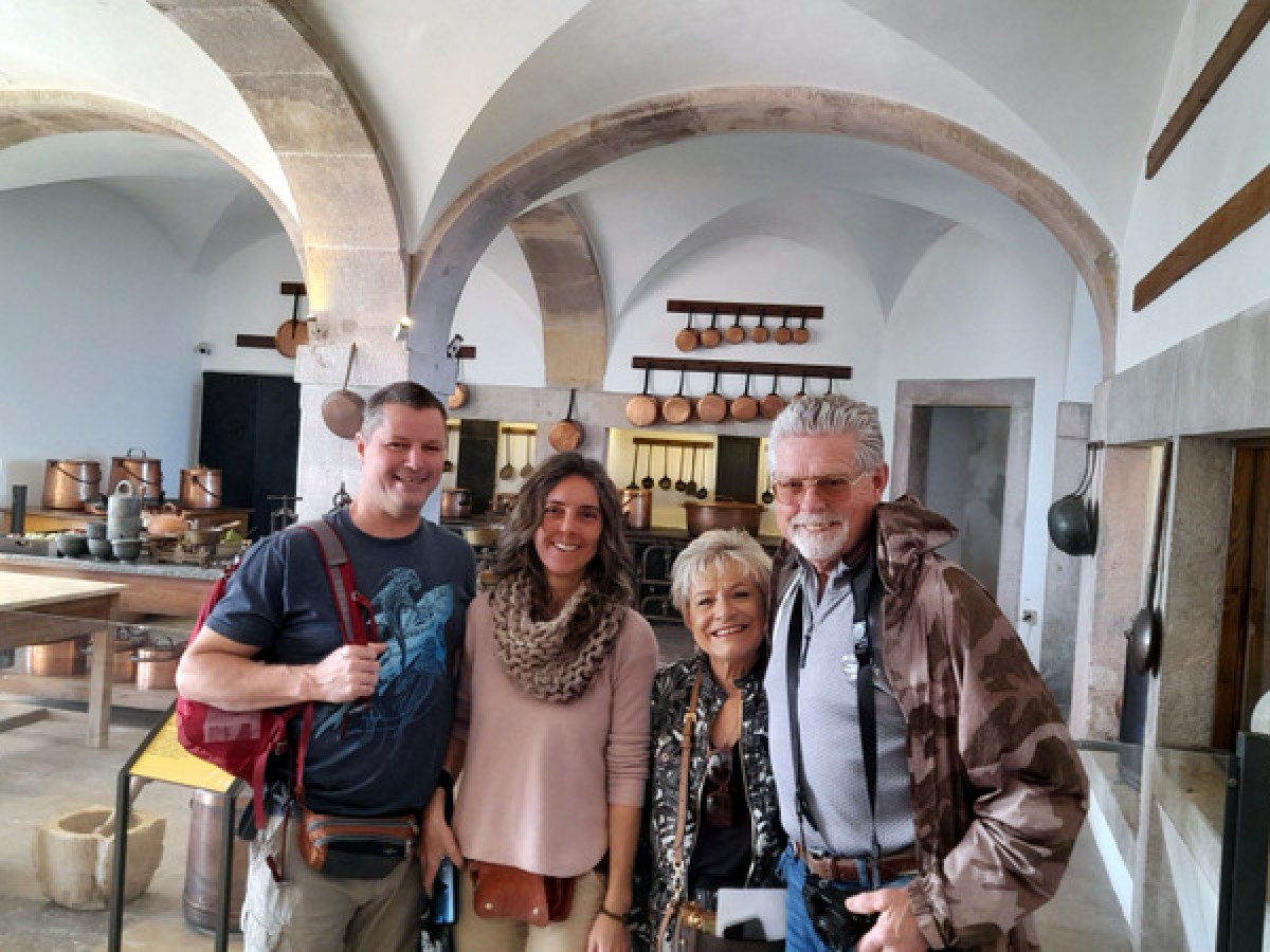 A cheerful group of people smiles for a photo in the historic kitchen of Pena Palace.