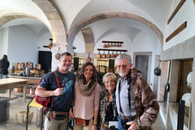 A cheerful group of people smiles for a photo in the historic kitchen of Pena Palace.