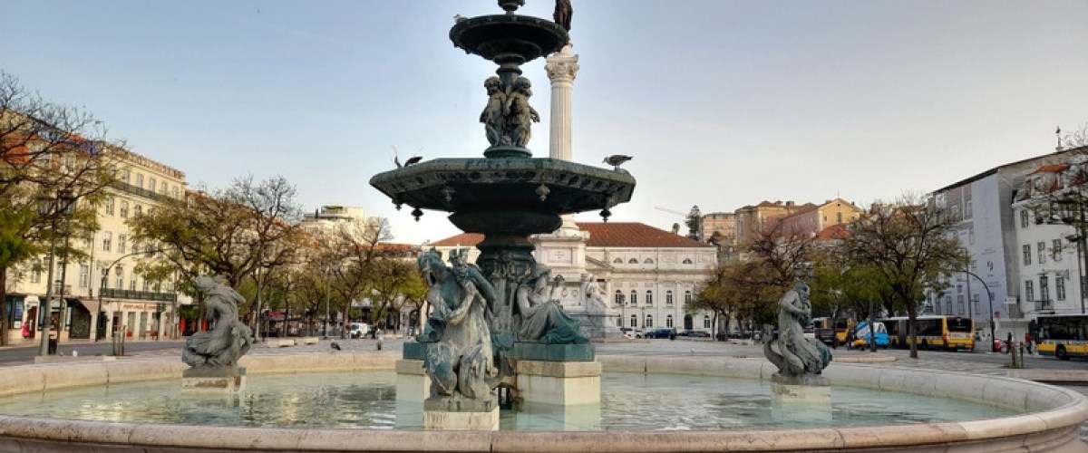 a fountain in front of a statue rossio lisbon
