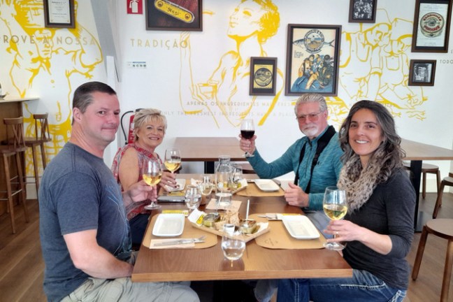 a group of people sitting at a dinner table posing for the camera sardine fatory tour