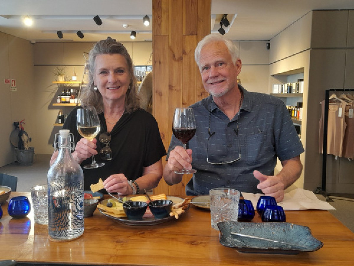 A couple enjoys a food tasting experience, seated at a table with wine glasses, savoring delicious Porto flavors together.