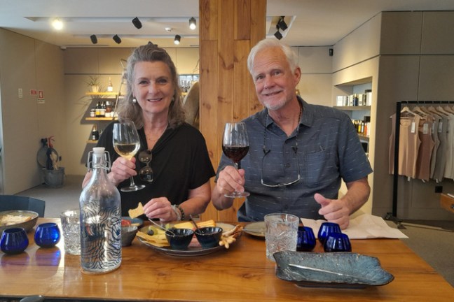 A couple enjoys a food tasting experience, seated at a table with wine glasses, savoring delicious Porto flavors together.
