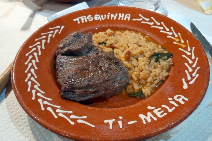 A delicious plate featuring cachena steak served alongside fluffy rice, ready to be enjoyed.