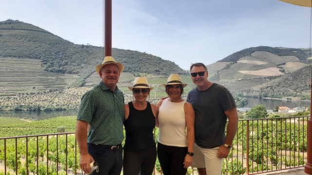 Four friends stand on a balcony, admiring the majestic mountains of Douro Valley after a memorable hiking tour.