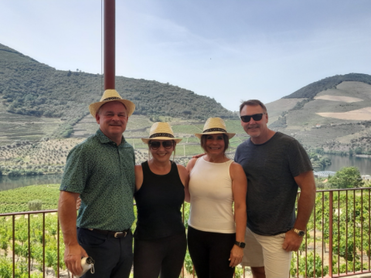 Four friends stand on a balcony, admiring the majestic mountains of Douro Valley after a memorable hiking tour.