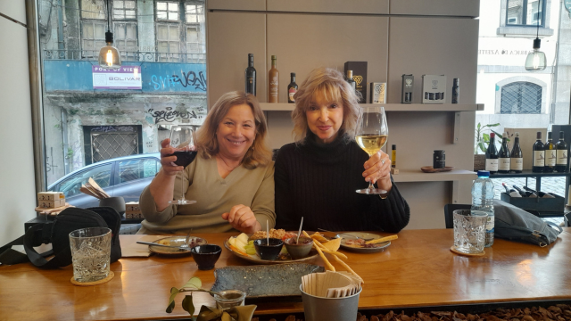 Two women savoring wine together at a table, sharing stories and smiles during a delightful food tour in Portugal.