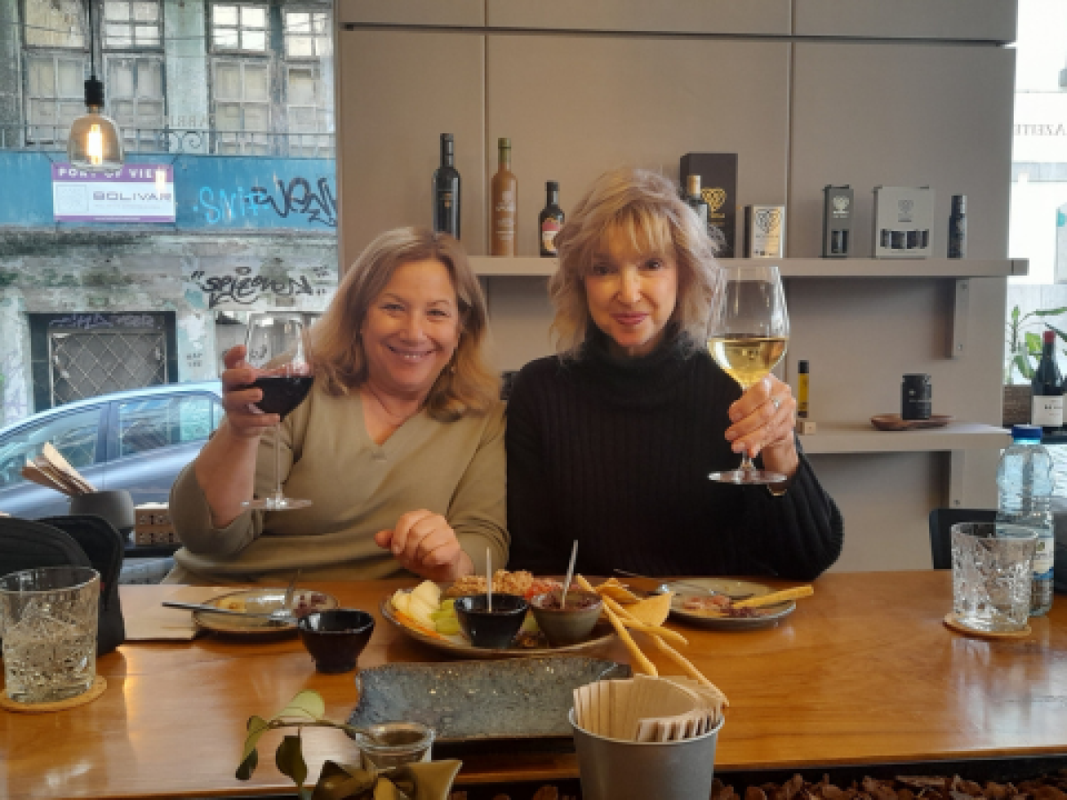 Two women savoring wine together at a table, sharing stories and smiles during a delightful food tour in Portugal.