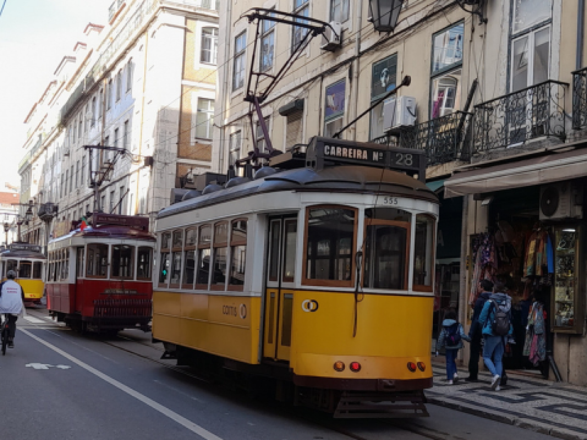 A picturesque street in Lisbon with a train passing through, showcasing the charm of the city's unique tours.