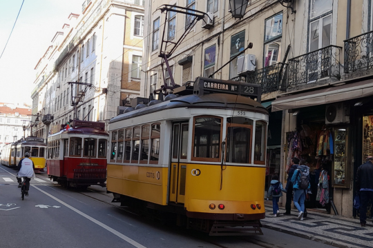 A picturesque street in Lisbon with a train passing through, showcasing the charm of the city's unique tours.