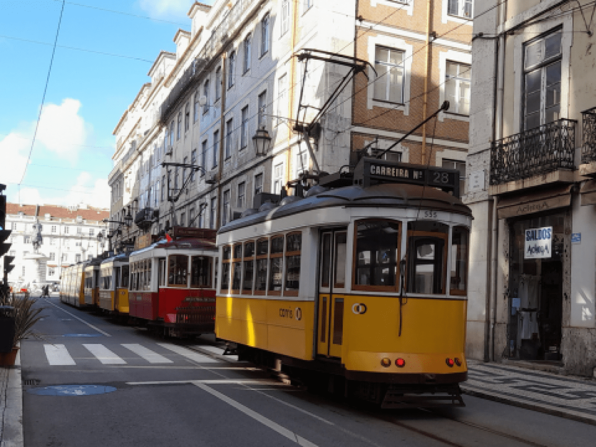 A lively Lisbon street adorned with a train, highlighting the excitement of exploring the city on a tour.