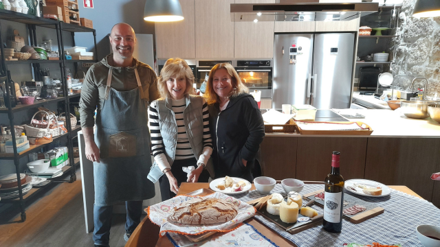 a group stand by a table brimming with food, celebrating the delights of a wine and food tour in Portugal.