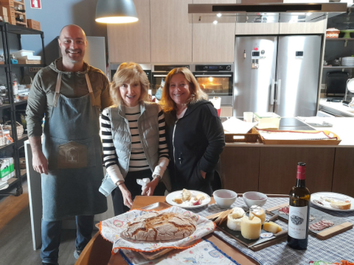 a group stand by a table brimming with food, celebrating the delights of a wine and food tour in Portugal.