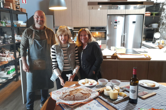 a group stand by a table brimming with food, celebrating the delights of a wine and food tour in Portugal.