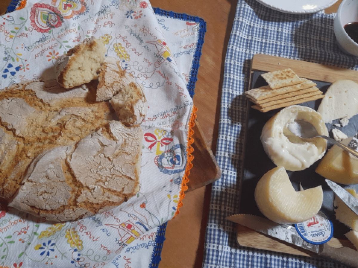 A rustic table set with a loaf of bread, cheese, and a knife, perfect for a wine and food tour in Portugal.
