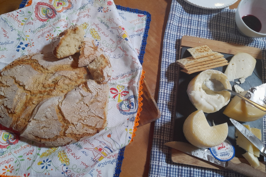 A rustic table set with a loaf of bread, cheese, and a knife, perfect for a wine and food tour in Portugal.