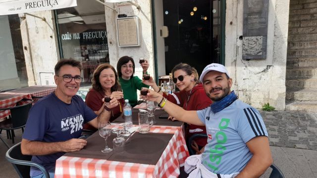 A lively group enjoying lunch together, clinking wine glasses during a 7-day tour in Portugal
