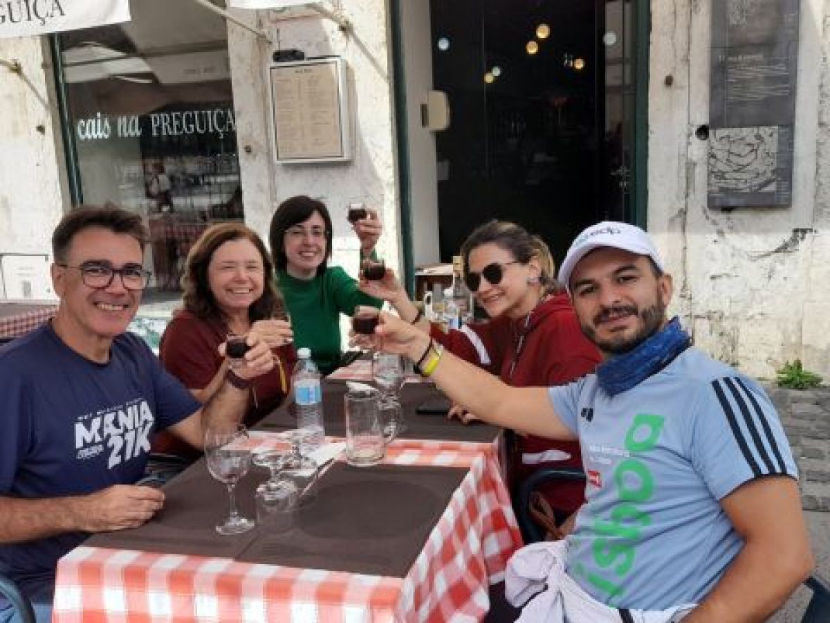A lively group enjoying lunch together, clinking wine glasses during a 7-day tour in Portugal