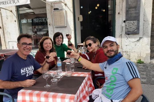 A lively group enjoying lunch together, clinking wine glasses during a 7-day tour in Portugal