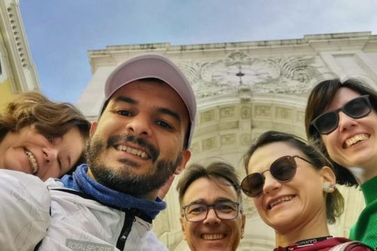 A family smiles for a selfie in front of an impressive building, making memories on their Portugal vacation.