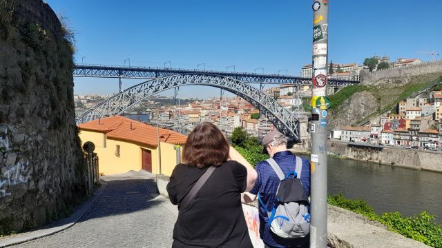 A couple stands on a bridge, admiring the Porto skyline during their 7-day tour, capturing a perfect moment together.