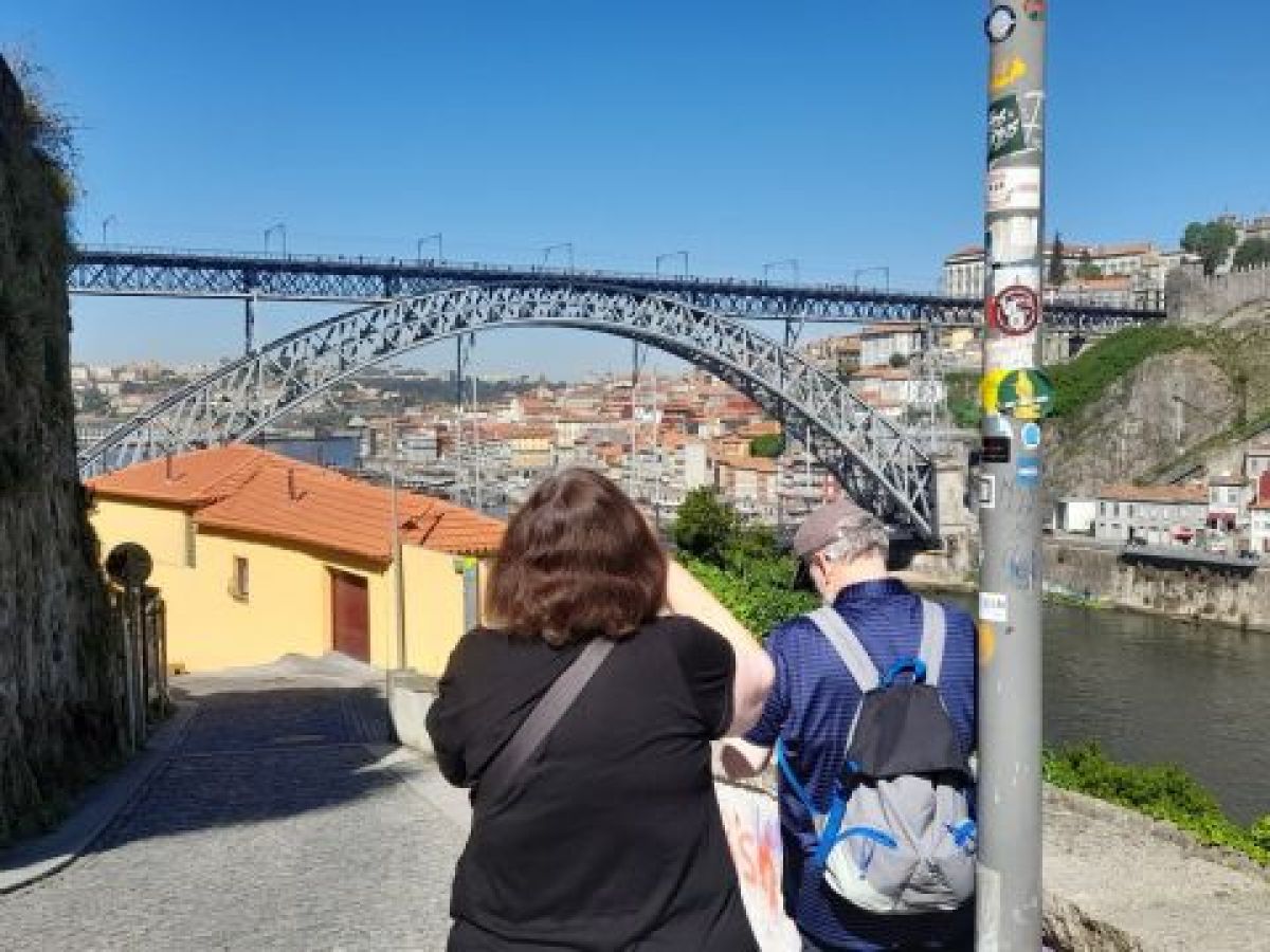 A couple stands on a bridge, admiring the Porto skyline during their 7-day tour, capturing a perfect moment together.