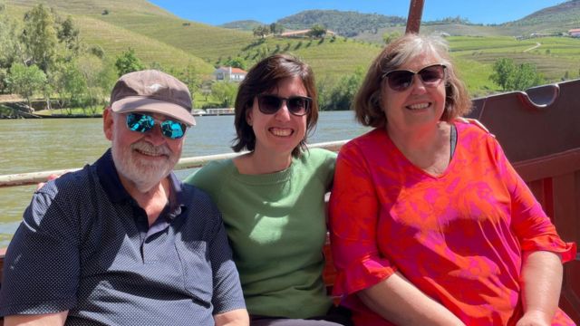 Three travelers relax on a boat, taking in the scenic Douro River during their 7-day tour in Portugal.