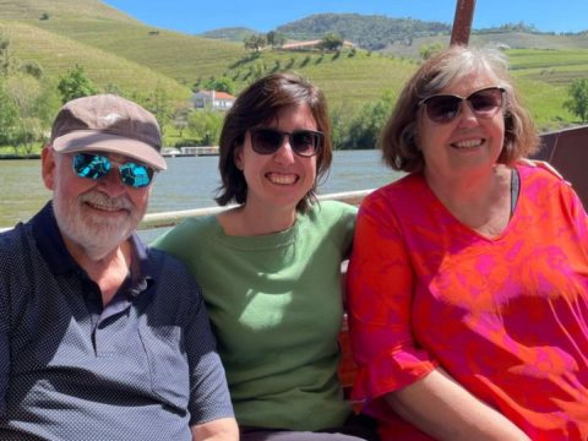 Three travelers relax on a boat, taking in the scenic Douro River during their 7-day tour in Portugal.