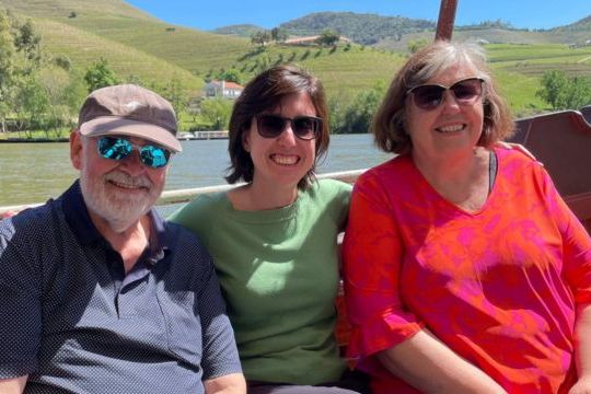 Three travelers relax on a boat, taking in the scenic Douro River during their 7-day tour in Portugal.