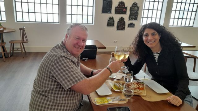 A couple enjoying sardines at a table during their cooking vacation in Portugal, sharing a delightful culinary experience.