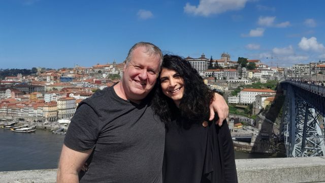A man and woman enjoy a scenic bridge view in Porto, immersed in their wine and food tour adventure.