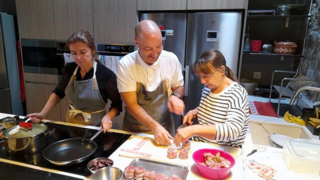 Two Portuguese chefs guide a group in a vibrant kitchen, sharing culinary skills during a vacation in Portugal.