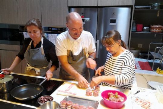 Two Portuguese chefs guide a group in a vibrant kitchen, sharing culinary skills during a vacation in Portugal.