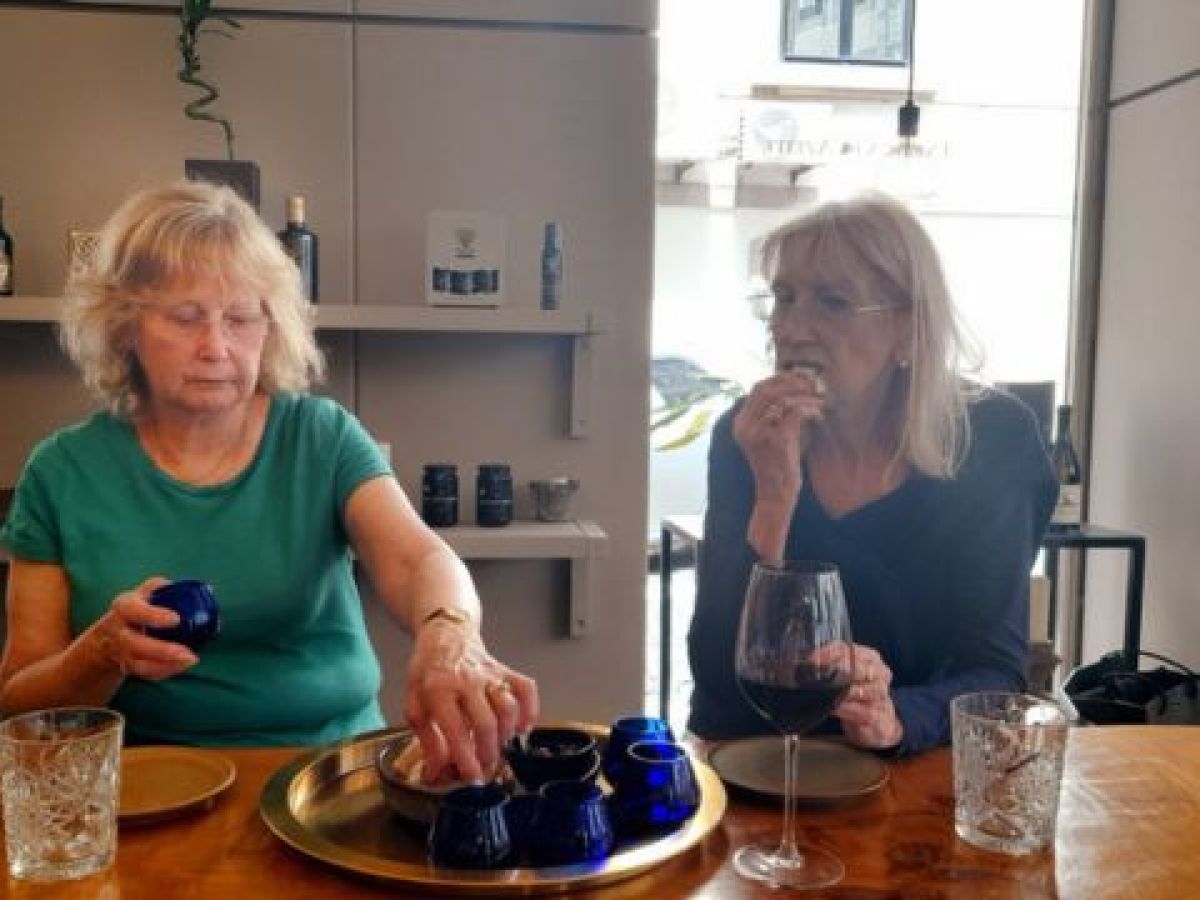 Two women, one in a green shirt, enjoy tasting olive oil together in Porto on a culinary vacation in Portugal.