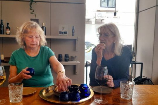 Two women, one in a green shirt, enjoy tasting olive oil together in Porto on a culinary vacation in Portugal.