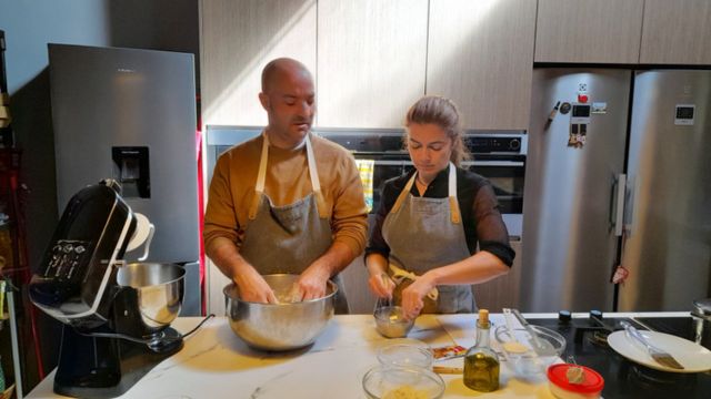 Two Portuguese chefs in a cozy kitchen, skillfully preparing dishes for a delightful dinner during a Lisbon food tour.