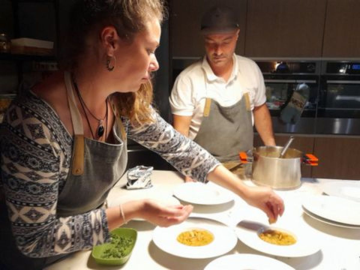 A woman dressed in a white shirt participates in a vibrant food and wine tour, savoring dishes prepared by local chefs in Lisbon.