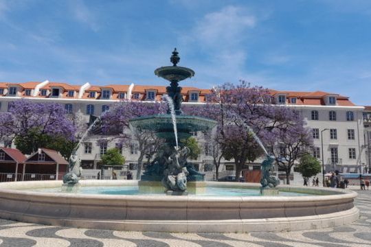 A charming city fountain surrounded by small groups enjoying their 7 Days in Portugal adventure from Lisbon.