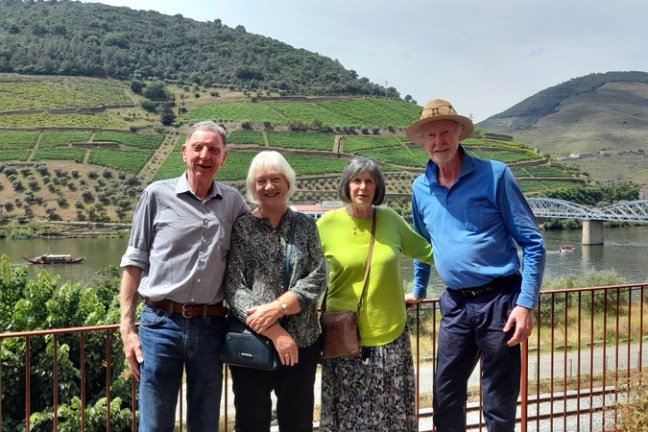 Four friends admire the scenic Douro valley from a bridge, capturing the essence of their small group journey in Portugal.