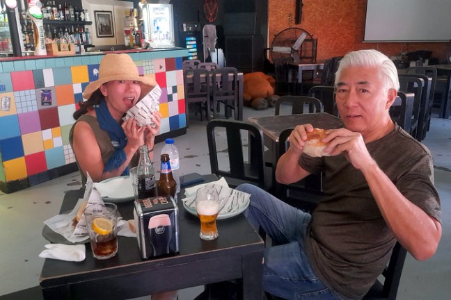 A couple seated at a table, relishing tasty bifana sandwiches while immersed in the flavors of a Braga food tasting tour.