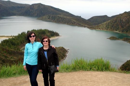A mother and daughter admire the stunning lake view from a mountain during their Azores family adventure.
