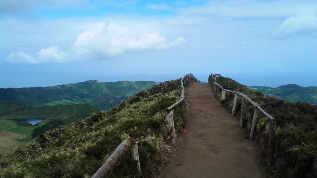 A beautiful trail leads to a stunning mountain in the Azores, with a picturesque sky and clouds enhancing the natural beauty of the scene.