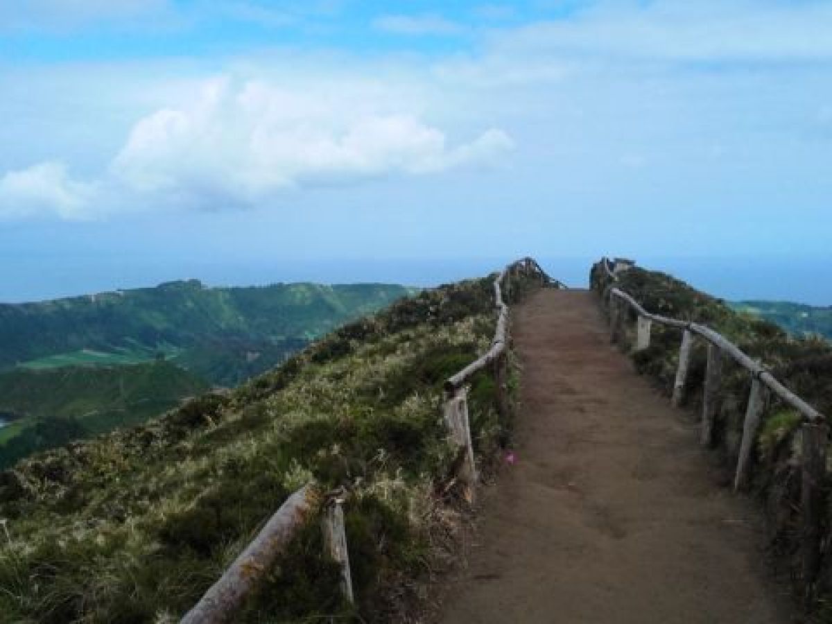 A beautiful trail leads to a stunning mountain in the Azores, with a picturesque sky and clouds enhancing the natural beauty of the scene.