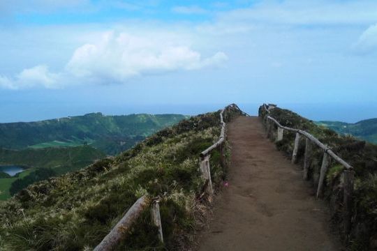 A beautiful trail leads to a stunning mountain in the Azores, with a picturesque sky and clouds enhancing the natural beauty of the scene.