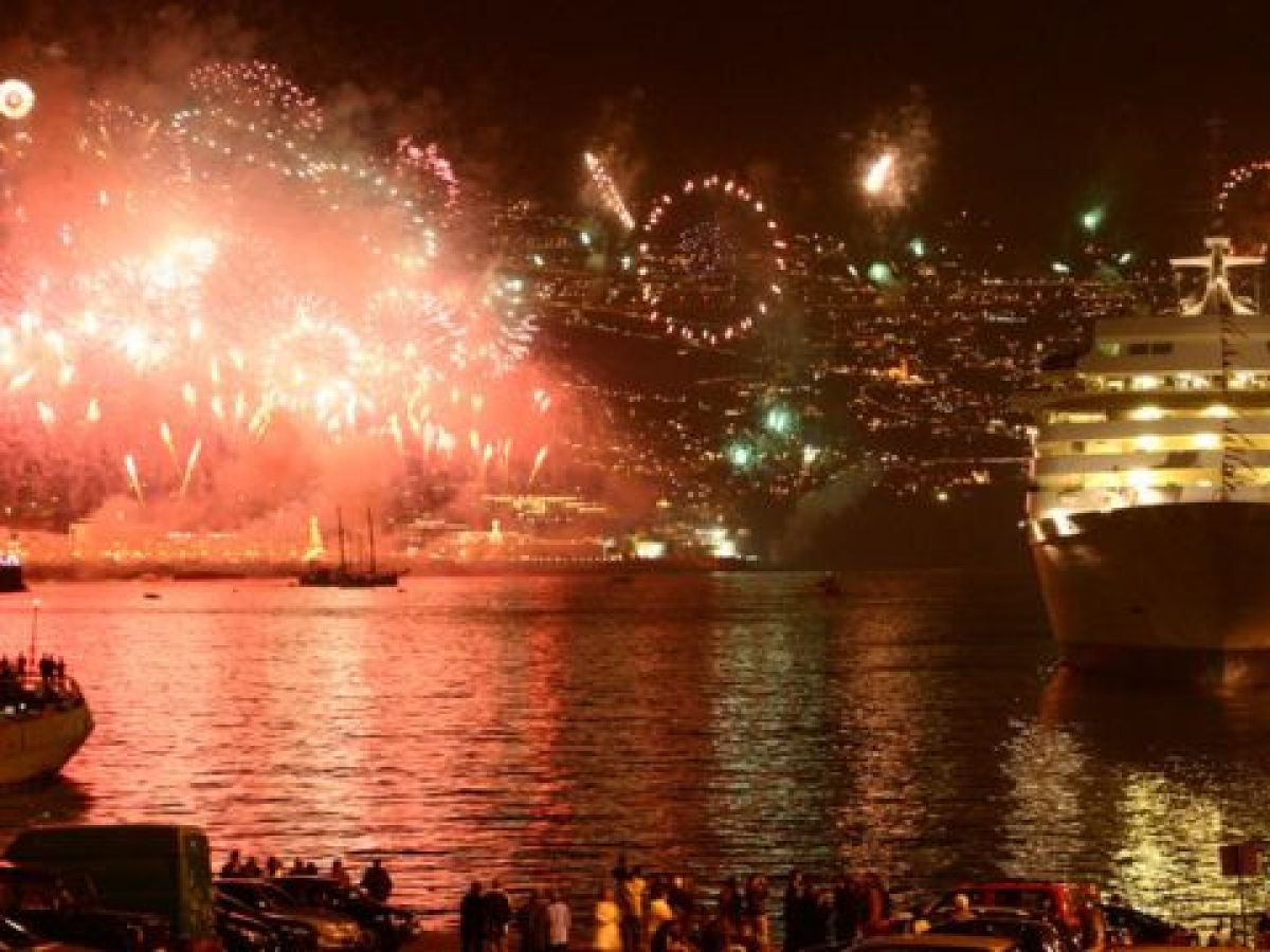 The vibrant fireworks illuminate the large body of water in Funchal, Madeira, creating a magical New Year's scene.