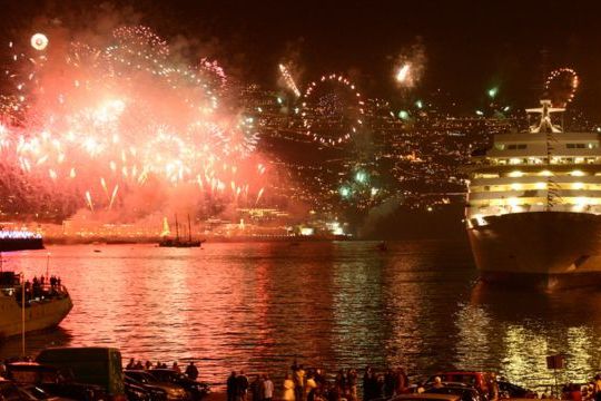 The vibrant fireworks illuminate the large body of water in Funchal, Madeira, creating a magical New Year's scene.