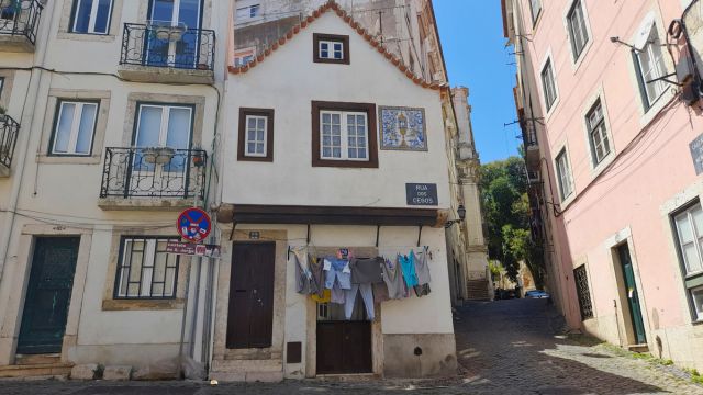 A picturesque narrow street in Lisbon, featuring unique buildings and a clear blue sky, ideal for non-touristy adventures.