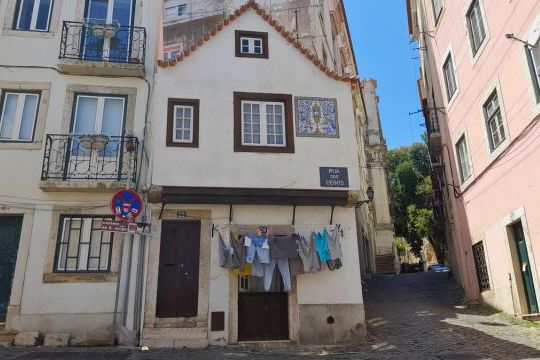 A picturesque narrow street in Lisbon, featuring unique buildings and a clear blue sky, ideal for non-touristy adventures.