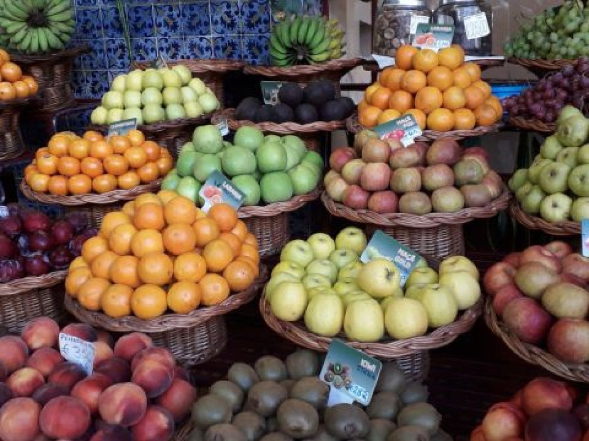 A cluster of fresh fruits hanging from the ceiling, highlighting the lively atmosphere of Funchal's markets in Madeira.