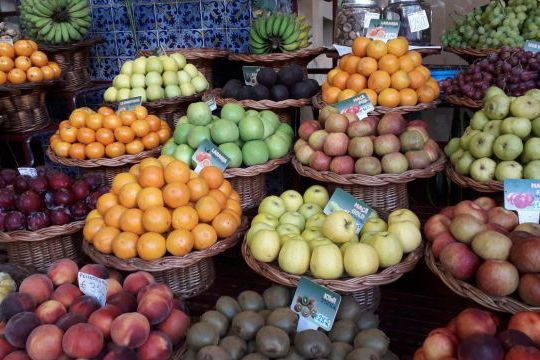 A cluster of fresh fruits hanging from the ceiling, highlighting the lively atmosphere of Funchal's markets in Madeira.